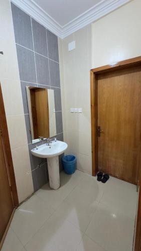 a bathroom with a sink and a mirror and a door at غيوم ابها - شقق مخدومه in Abha