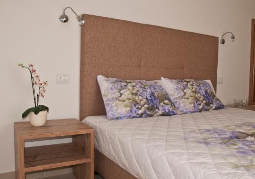 a bed with a headboard and a table with a vase on it at Villa delle Querce in Tremosine Sul Garda