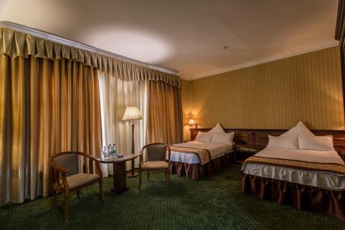 a hotel room with two beds and a table and chairs at Karvon-Saroy Hotel in Andijan