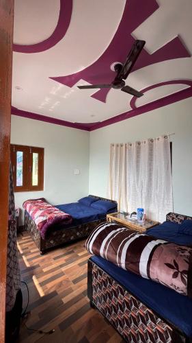 two beds in a room with a ceiling fan at Chaukhamba Pine Cottage & HomeStay in Rānsi
