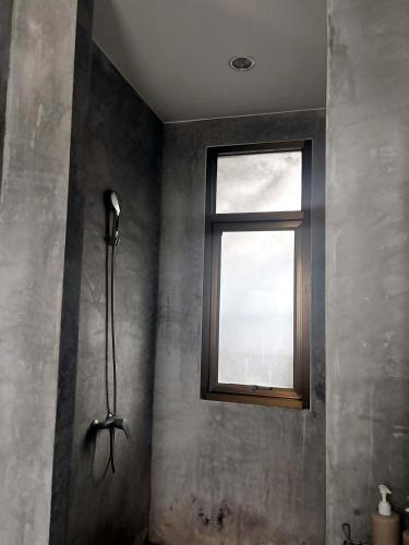 a shower in a bathroom with a window at Baan Phu Place in Ban Suan