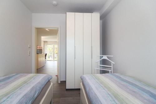 a bedroom with two beds and a white wall at Flott-am-Meer in Norddeich