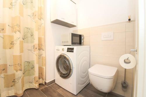 a bathroom with a washing machine and a toilet at Flott-am-Meer in Norddeich