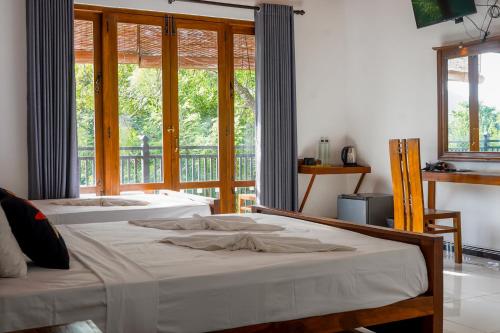 a bedroom with two beds and a large window at Lion See Hotel - Sigiriya in Sigiriya