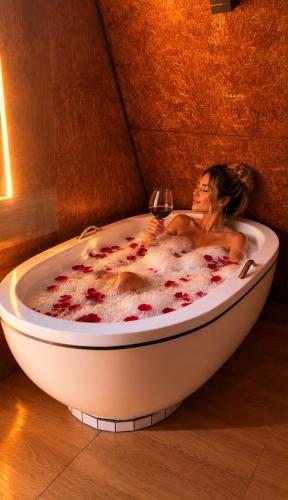 a woman in a bath tub with a glass of wine at Chalé Queen in Brasília