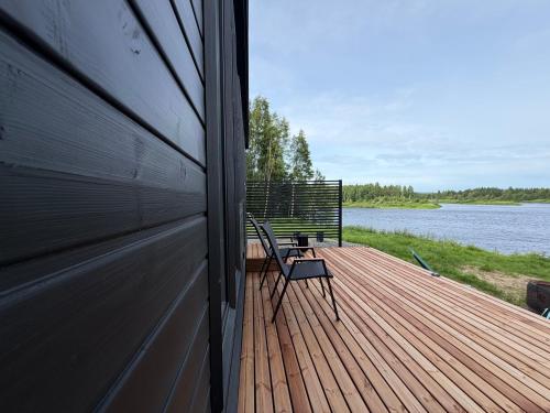 a wooden deck with a chair on the side of a house at Aurora Forest Cabin in Rovaniemi