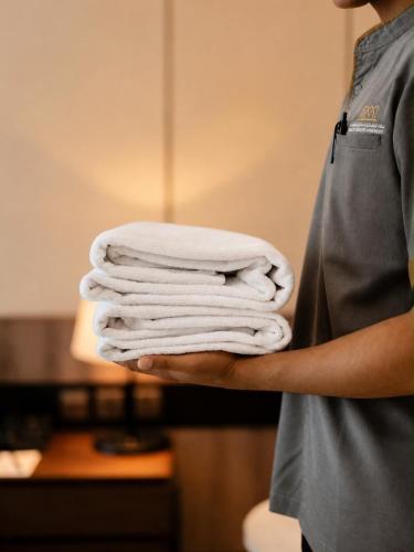 a person holding a stack of white towels at ملاذ للشقق المخدومة in Salalah