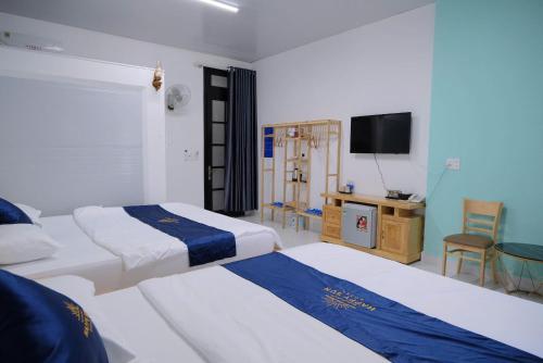a bedroom with two beds and a flat screen tv at Happy Sun Hotel in Mỹ Tho