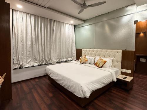 a bedroom with a bed with white sheets and a window at Hotel Ashoka Inn in Wardha