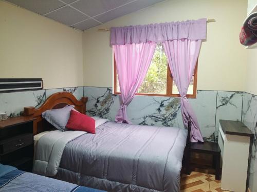 a bedroom with two beds and a window with pink curtains at Casa de campo san Andrés in Otavalo