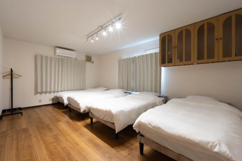a group of three beds in a room at Shima Yadori Ao in Oshima