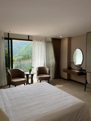 a bedroom with a bed and two chairs and a mirror at Muong Thanh Luxury Moc Chau Hotel in Mộc Châu