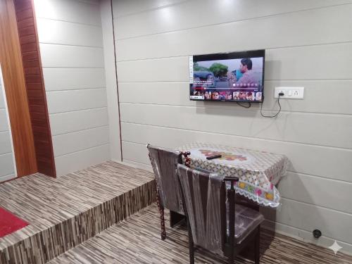 a room with a table and a tv on the wall at Hotel Garden Lodging And Boarding in Ulhāsnagar