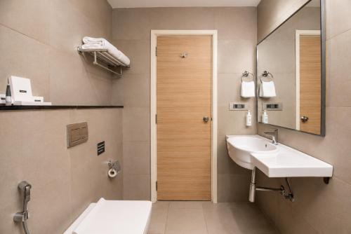 a bathroom with a sink and a mirror and a toilet at Hotel Star City in Chennai
