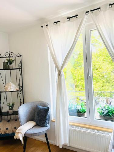 a chair in front of a window with curtains at SEEMOMENTE Überlingen Promenade in Überlingen
