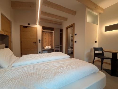 a bedroom with a large white bed and a table at Liz Hotel & Apartments in Predazzo