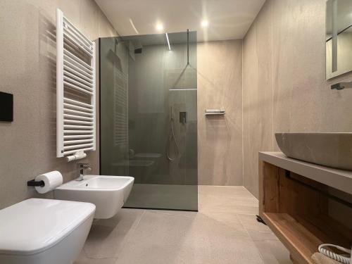 a bathroom with a shower and a toilet and a sink at Liz Hotel & Apartments in Predazzo