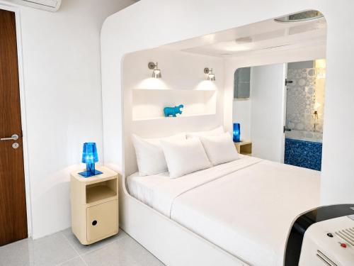 ein weißes Schlafzimmer mit einem Bett und blauen Vasen in der Unterkunft Chill Hotel Seminyak in Seminyak