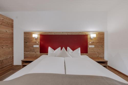 a bedroom with a large white bed with a red headboard at Landhaus Waldesruh in Oetz