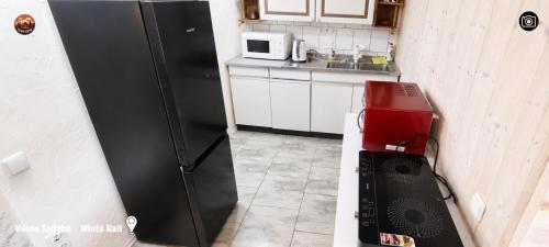 a kitchen with a black refrigerator and a microwave at Vilimu Sodyba - White Hall in Kriukai