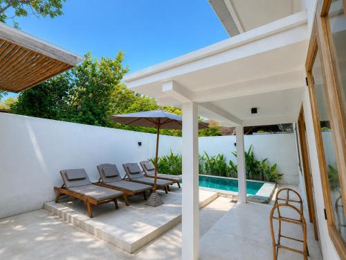a patio with chairs and an umbrella next to a pool at Villa Marieta - Two Bedrooms Private Villa in Kuta Lombok