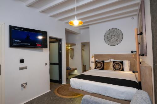 a bedroom with a bed and a tv on the wall at Double Mini Suites Adults Only in Ano Mera
