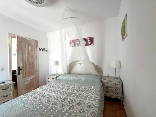 a white bedroom with a bed and two night stands at Casa Maena in Cómpeta