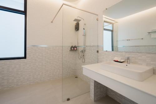 a white bathroom with a sink and a shower at เจ้าหลาว ซี บรีส รีสอร์ท in Ban Mu Dut
