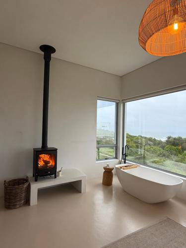 a bathroom with a bath tub and a fireplace at Atlantic Corner in Yzerfontein