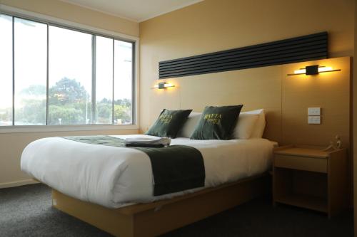 a bedroom with a large bed and a large window at Rayya Suites , Invercargill in Invercargill