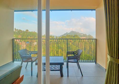 a room with a balcony with a table and chairs at Nature Green Pool Resort Munnar by VOYE HOMES in Munnar