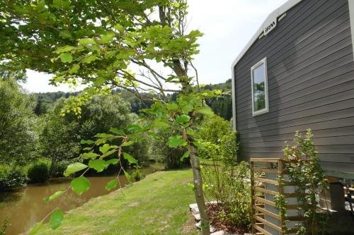 a house with a tree next to a river at Sideschlee Chalet aan het water in Wintger