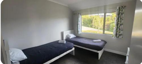 two beds in a small room with a window at Casa Del Sol in Riwaka