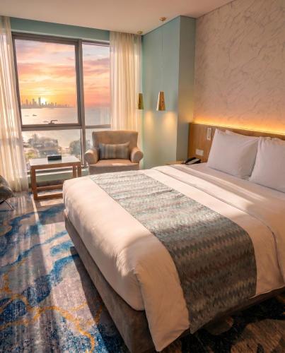 a hotel room with a large bed and a chair at Symphony Style Hotel Kuwait in Kuwait