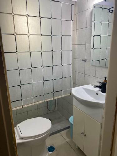 a white bathroom with a toilet and a sink at Calypso Rooms in Preveza