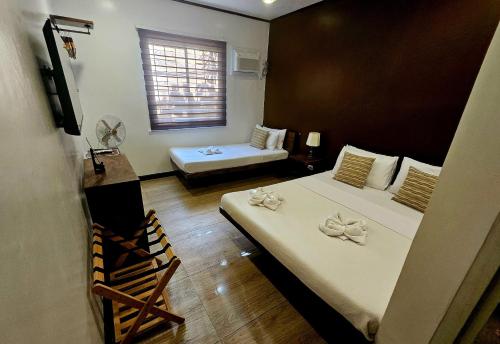 a hotel room with two beds and a window at Cleon Villas Pension in Puerto Princesa City