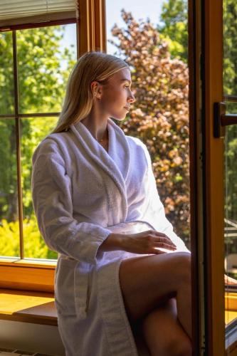 a woman sitting in a towel looking out of a window at Niedźwiedzia Residence Garden & Sauna in Poronin