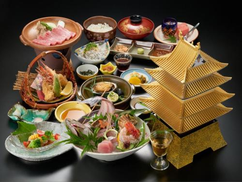 a table topped with plates of food and bowls of food at Tabist Yuasa Castle Onsen Hotel in Yuasa