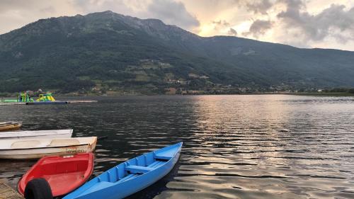 three boats sitting on the water near a mountain at Sunčani Brijeg Eco Village in Plav