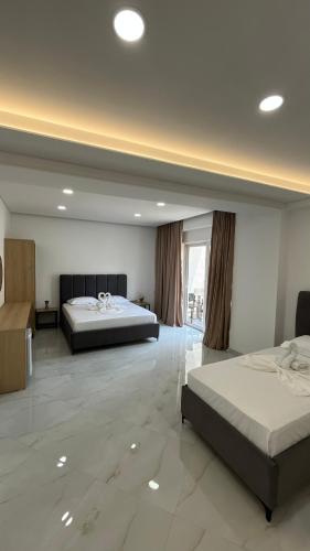 a large room with two beds and a large window at Laska's Rooms Sarandë in Sarandë