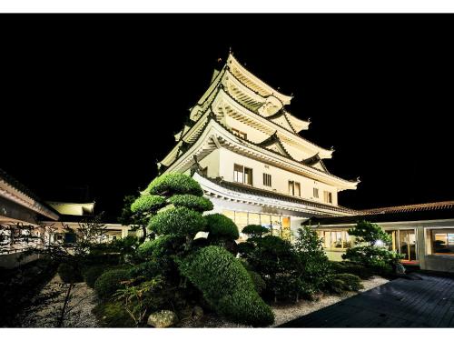 a large white building with a clock tower at night at Tabist Yuasa Castle Onsen Hotel in Yuasa