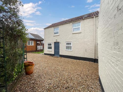 a white house with a blue door and a yard at Bacchus Cottage - Uk51964 in Sutton on Sea
