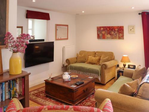 a living room with a couch and a tv at The Quarry Stables in Cheddar