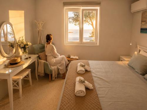 a woman sitting in a bedroom looking out the window at Ni&Gio Sterna 6 in Parikia