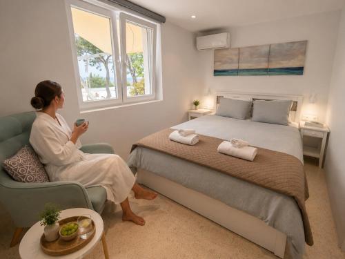 a woman sitting in a chair next to a bed at Ni&Gio Sterna 6 in Parikia