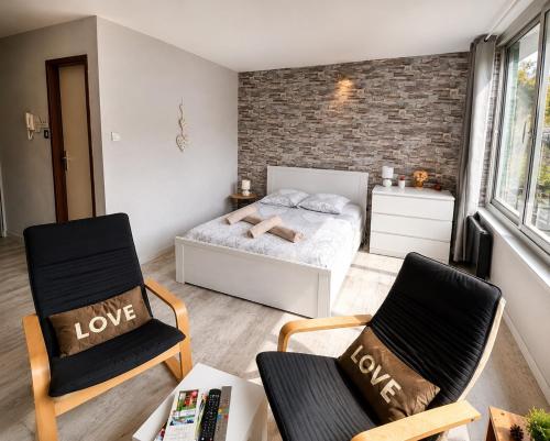 a bedroom with a bed and two chairs at Petit Nid Nature Et Douceurs in Turckheim