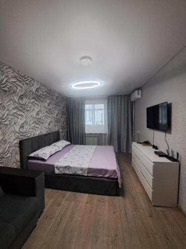 a bedroom with a bed and a tv and a couch at Ткачёва in Pavlodar