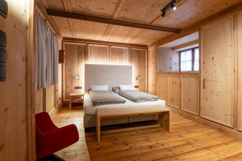 a bedroom with a bed and a red chair at Premium Apartments Faselehof in Marlengo