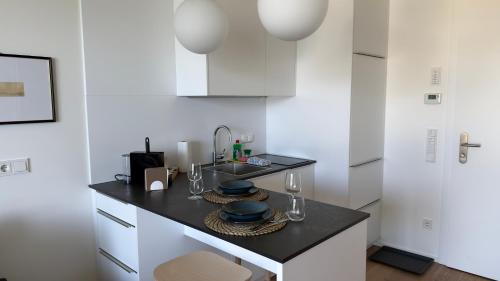 a kitchen with a sink and a counter with plates and glasses at Hermitage Apartment E03B - Seeblick & Zugang in Maria Wörth