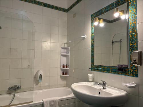 a bathroom with a sink and a tub and a mirror at Bay Palace Mazzarò in Taormina